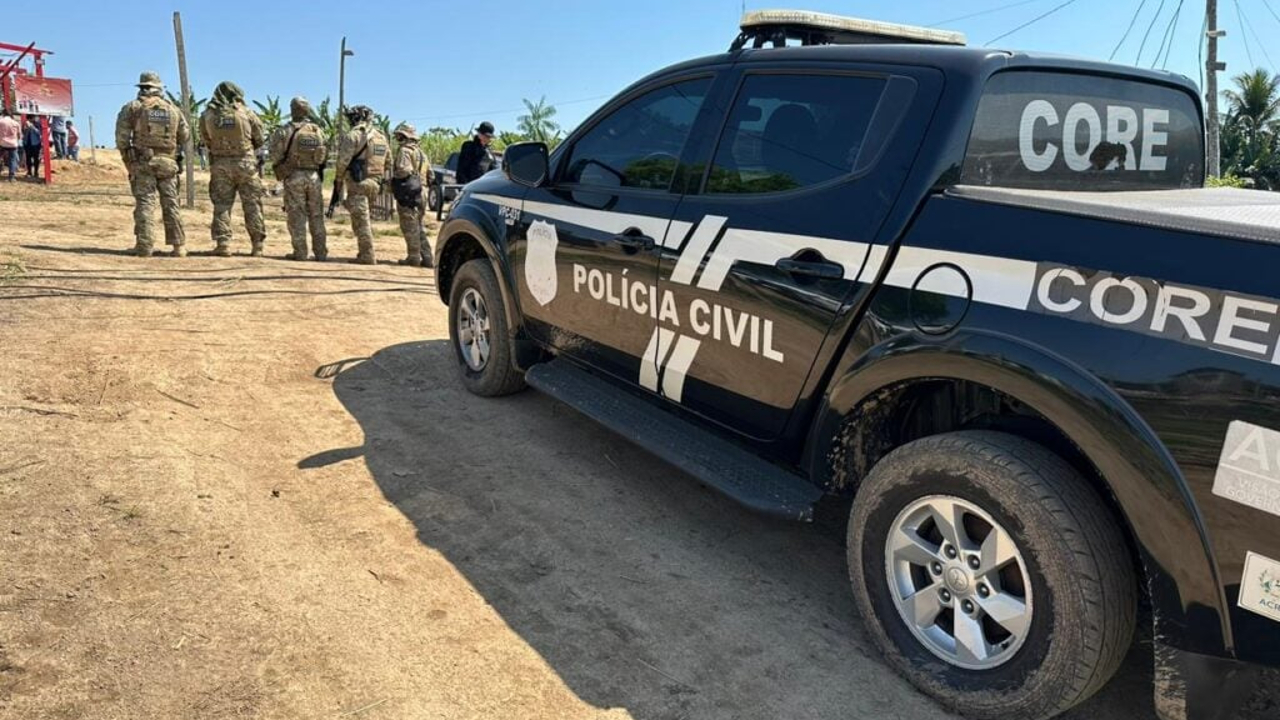 Viatura preta da Polícia Civil do Acre com agentes fardados em operação ao fundo em área aberta